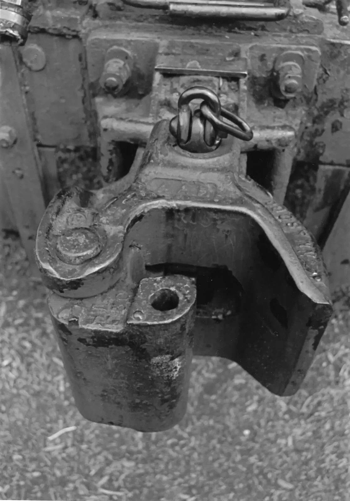 Close-up of a tow hitch receiver with safety chains and wiring plug under a vehicle bumper