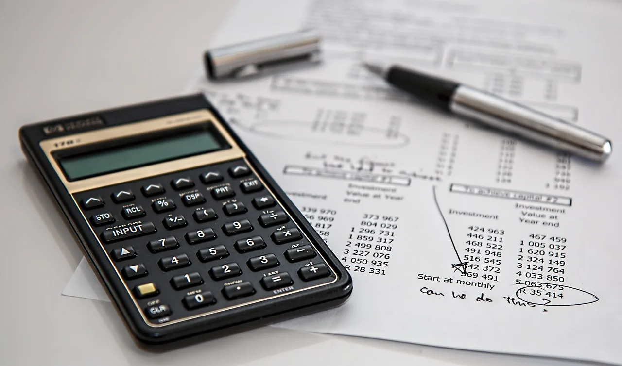 Couple reviewing a car finance quote with calculator and paperwork at a kitchen table