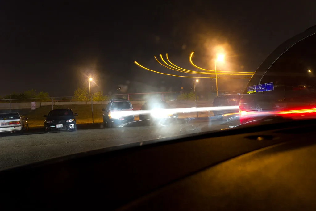 Hands adjust dash cam parking mode settings beside a windshield-mounted camera