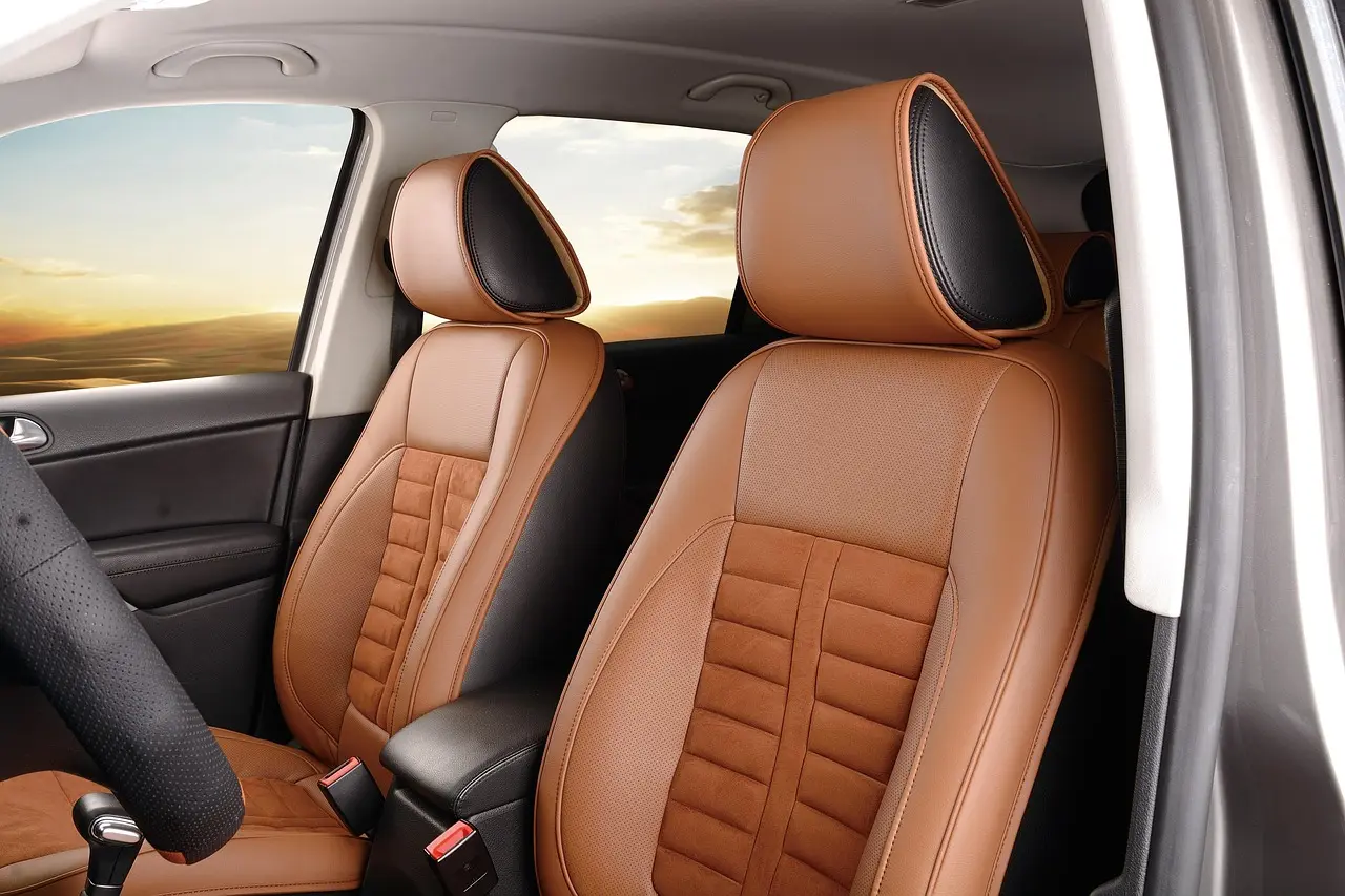 New car owner with a leather care kit beside a sedan and tan leather interior in natural light
