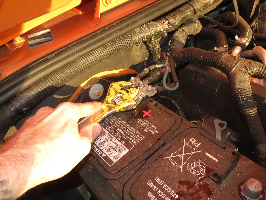Close-up of corroded car battery terminals being cleaned with a wire brush