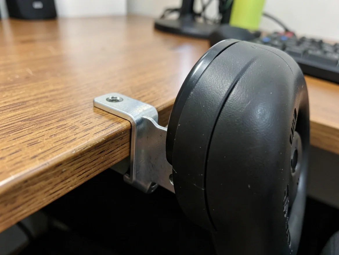 Metal desk clamp mounting a racing wheel base to the edge of a desk