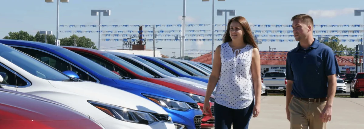 Couple walking through a row of new cars on a dealership lot