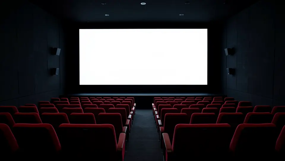 An empty movie theater with red seats facing a blank screen
