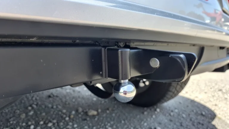 Close-up of a trailer hitch receiver and tow ball mounted under the rear bumper of an SUV
