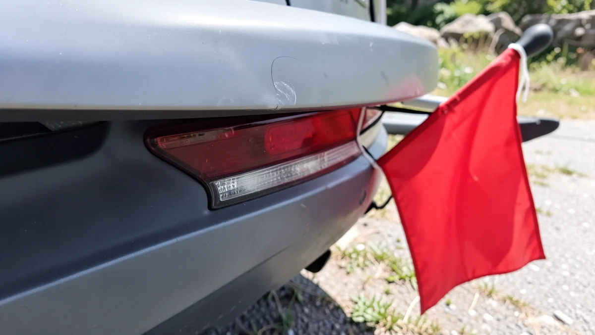 Red safety flag tied to the rear end of a kayak that overhangs the back of a car roof rack