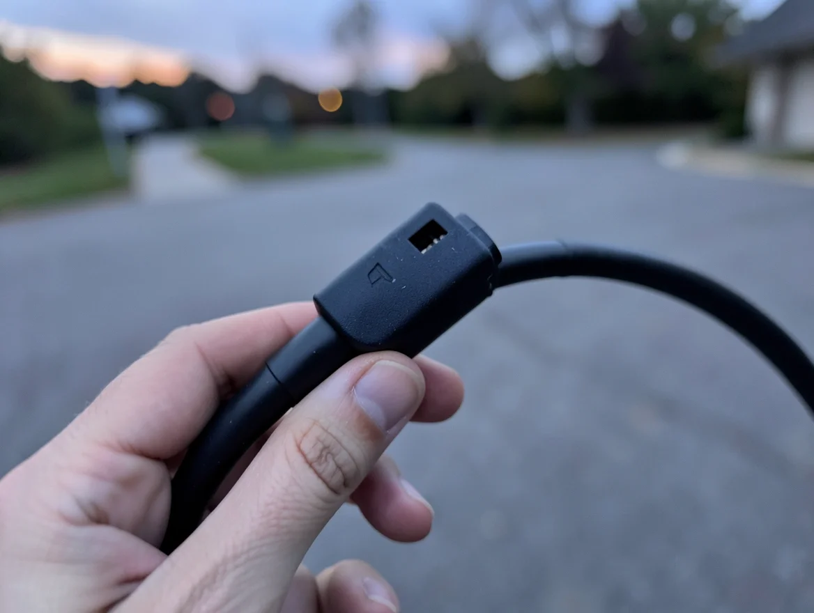 Person holding an EV charging connector, illustrating how electric car mileage limits differ from gas cars