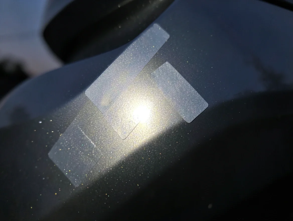 Reflective safety stickers on a car bumper corner glinting at dusk for visibility