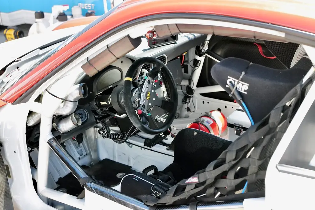 Sprint car cockpit close-up with exposed suspension and a driver adjusting the controls.
