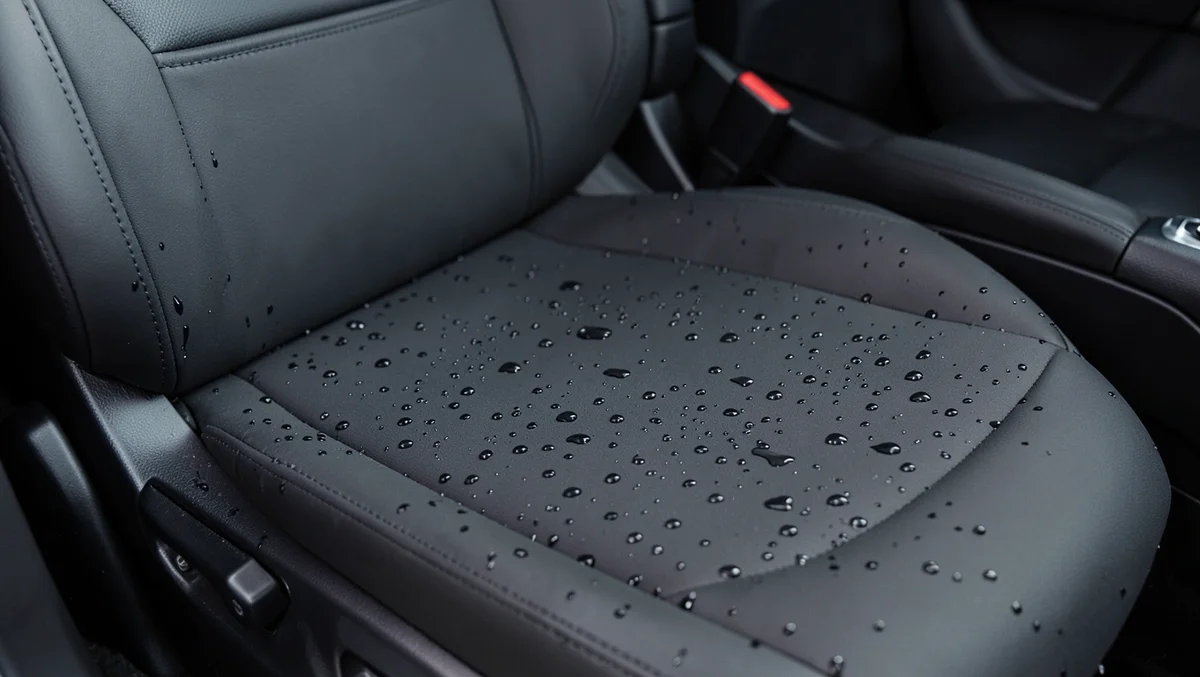 Black waterproof car seat cover beading water droplets on the surface