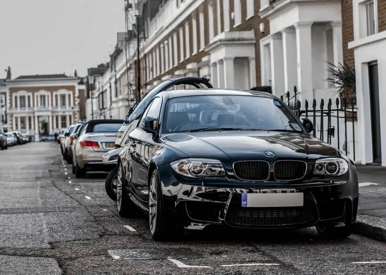 2026 BMW 328i parked at a fuel station while a driver reviews trip mileage in warm natural light