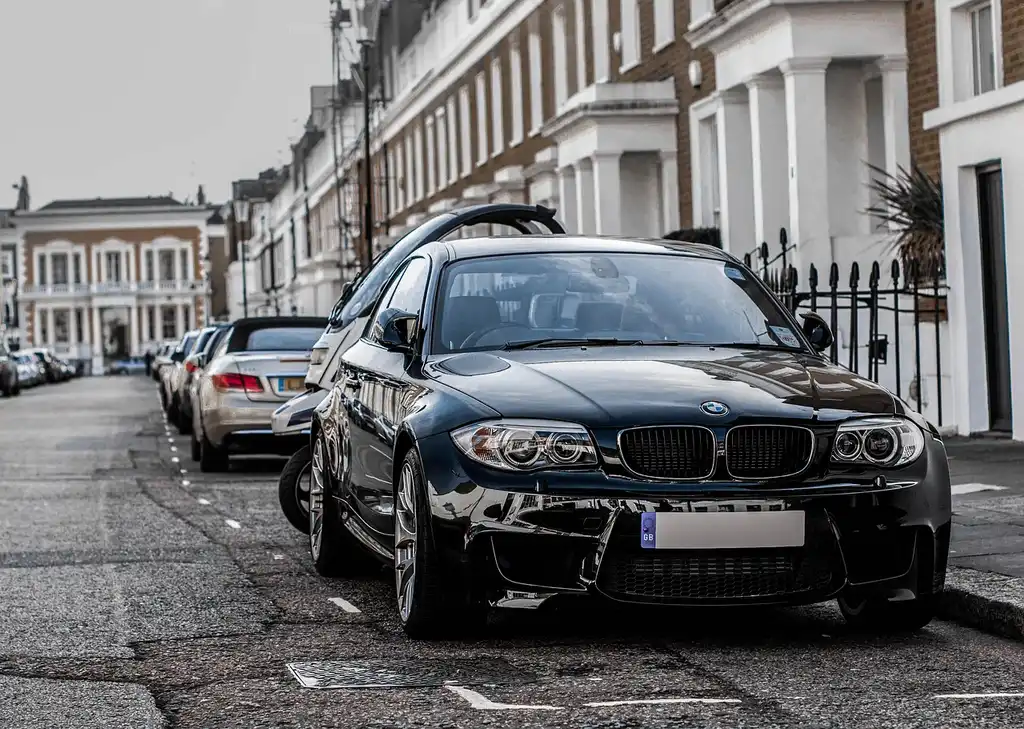 2026 BMW 328i parked at a fuel station while a driver reviews trip mileage in warm natural light