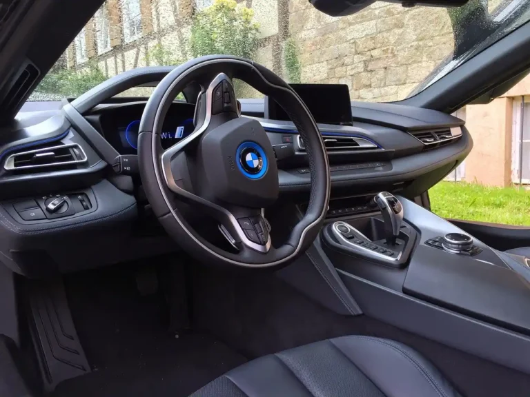 2026 BMW X5 4.4i with hood open on a driveway, mechanic and owner inspecting the engine bay