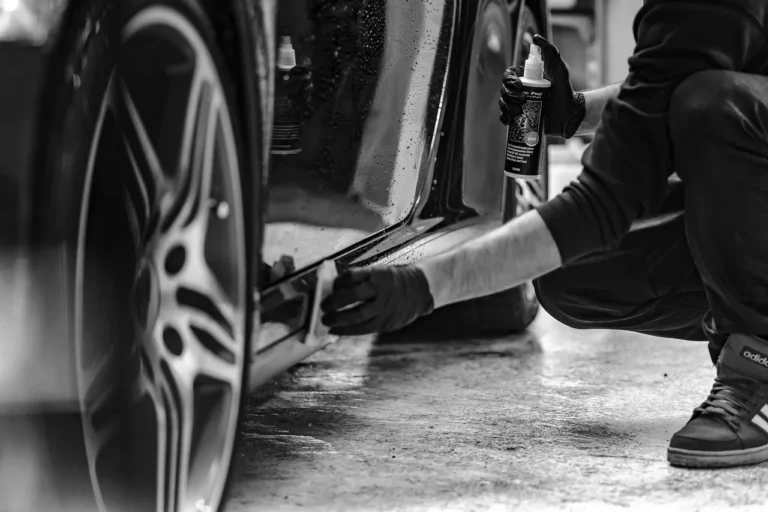 Three car cleaning gloves beside a silver sedan in natural daylight