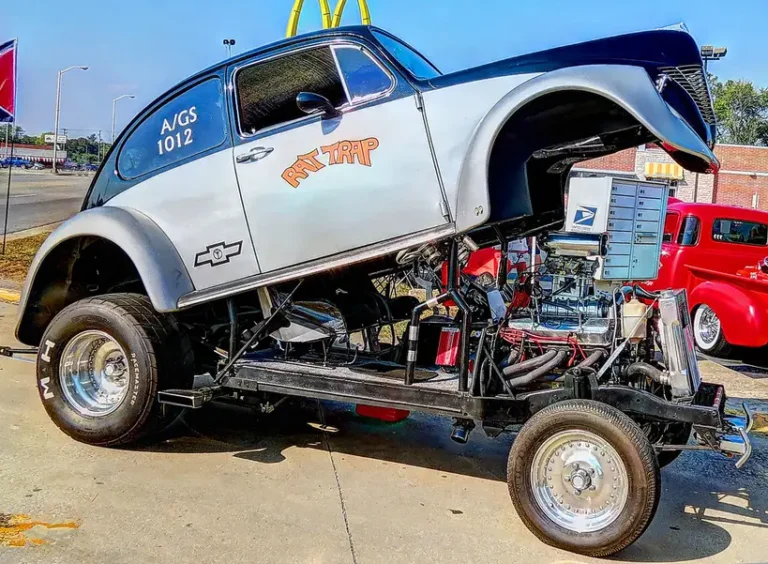 A classic Chevy 302 engine on a stand in a bright garage with visible stamped block numbers.