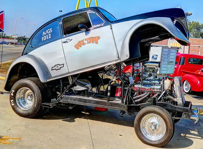 A classic Chevy 302 engine on a stand in a bright garage with visible stamped block numbers.