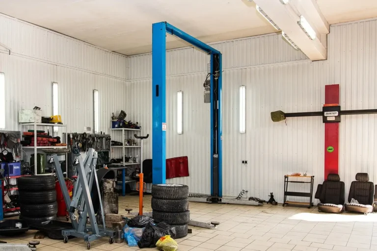 Auto Service Can shop front with a mechanic and customer near a parked car at golden hour