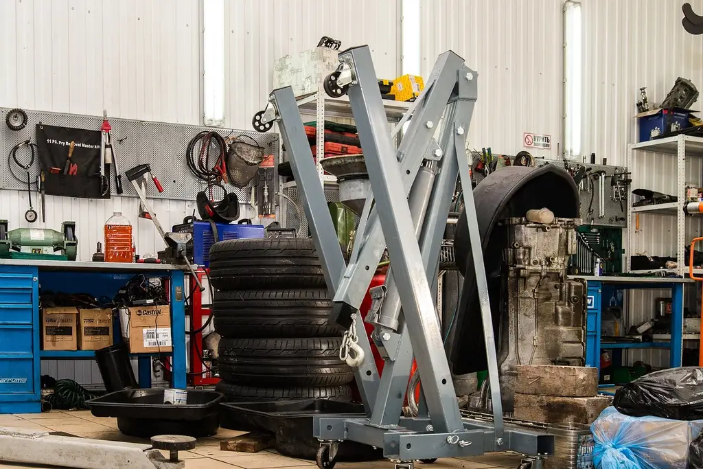 Automotive technology workshop with a technician, open-hood sedan, diagnostic scanner, and EV service equipment