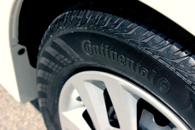 Sedan on a wet road with light snow, showing all-season tires in winter conditions