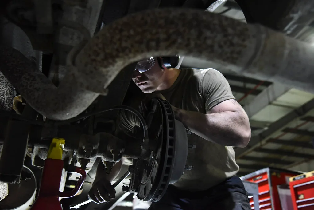 Close-up of a brake pad thickness check beside a rotor in a repair shop