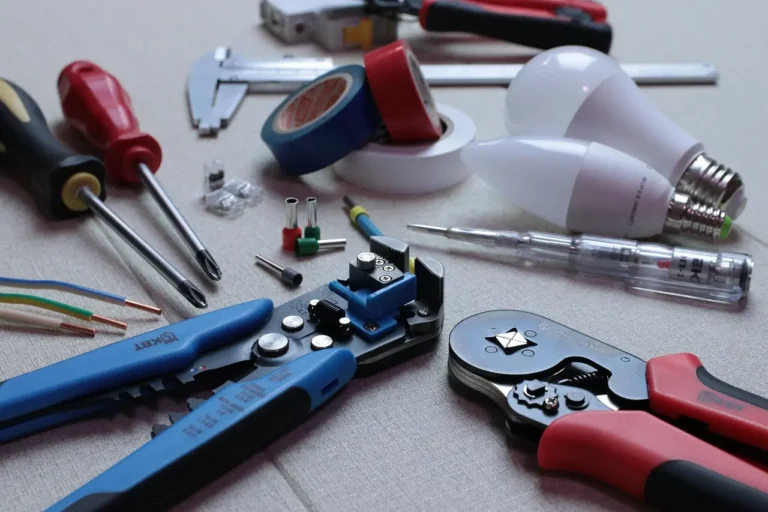 Three auto wire strippers on a garage workbench beside car wiring and connectors