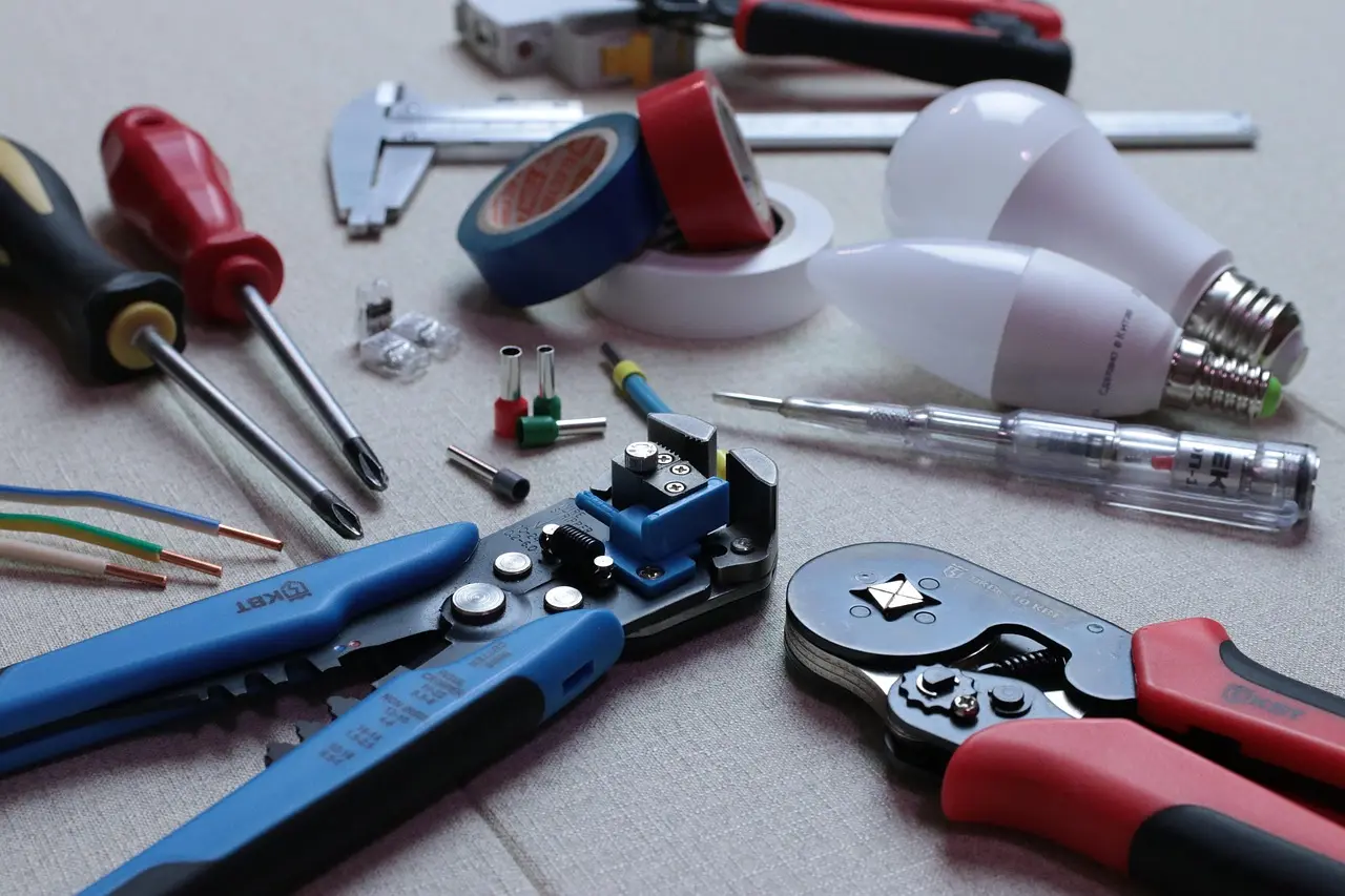 Three auto wire strippers on a garage workbench beside car wiring and connectors
