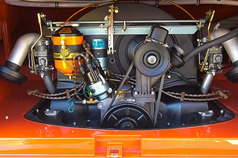 Three automotive belts beside an open car engine bay with pulleys and tensioner visible