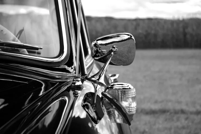 Car side mirrors with blind spot mirrors on a sedan and an SUV in driveway