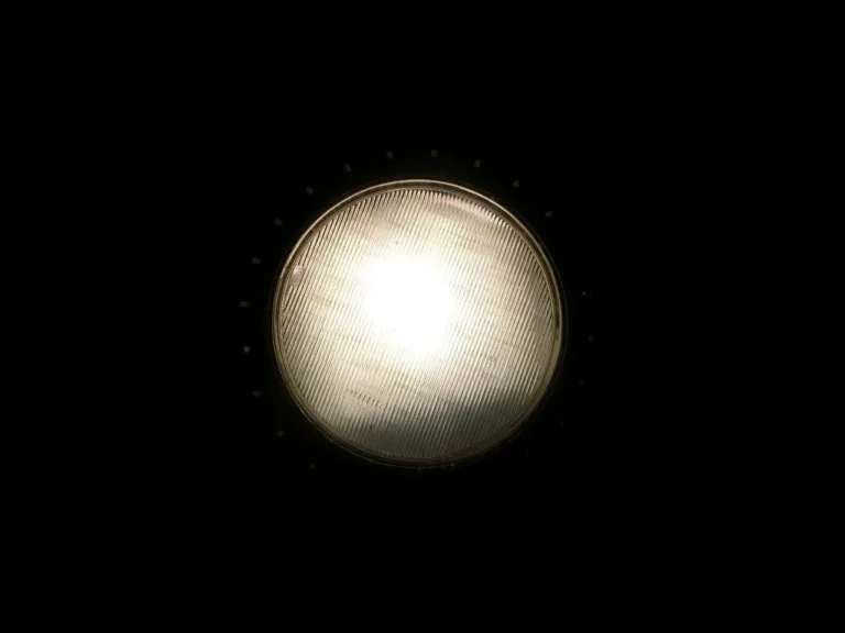 Car headlights shining on wet road at night with a person checking beam spread and fitment.