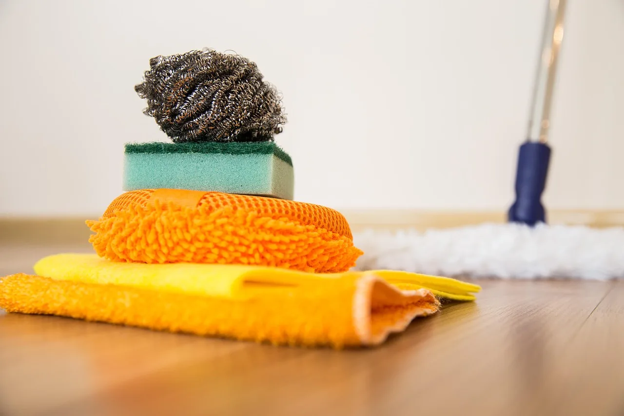 Microfiber buffing cloths beside a detailer polishing a blue car hood