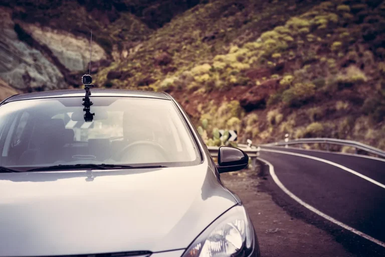 Car camera mounted inside a parked SUV, with a person approaching outside at dusk