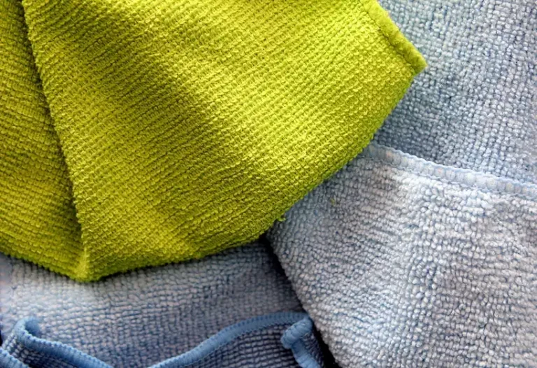Car cleaning cloths laid out beside a sedan in natural light