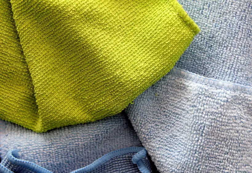 Car cleaning cloths laid out beside a sedan in natural light
