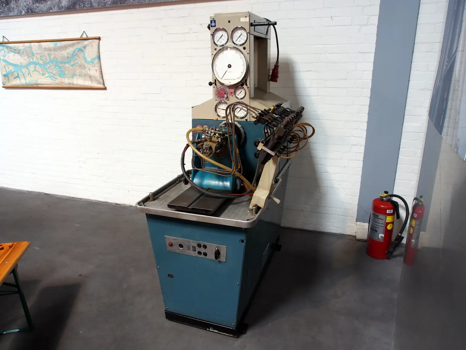 Technician comparing car fuel pumps beside a sports car and pressure gauge in a garage