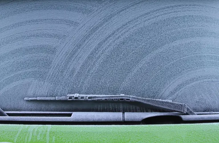 Three car ice removers on a frosty SUV hood in morning winter light.