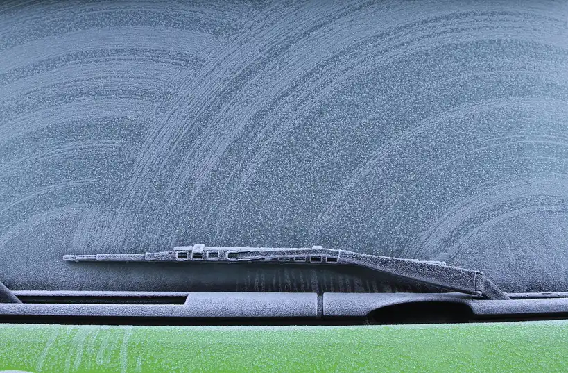 Three car ice removers on a frosty SUV hood in morning winter light.