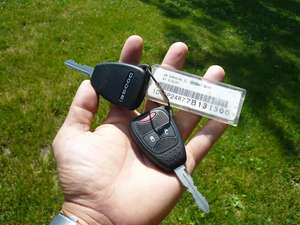 Hand comparing rental paperwork, keys, and a phone on a café table