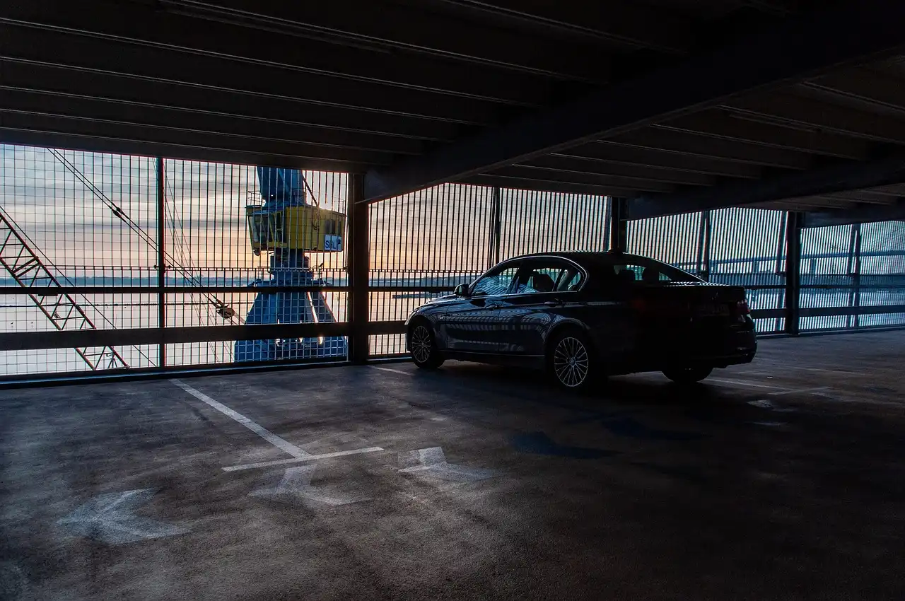 Driver reversing a sedan into a tight parking space with rear parking sensors visible