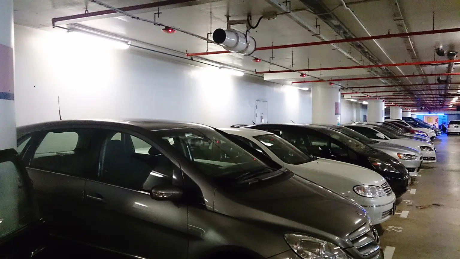 Hand fitting a reverse parking sensor into a car bumper with wiring exposed