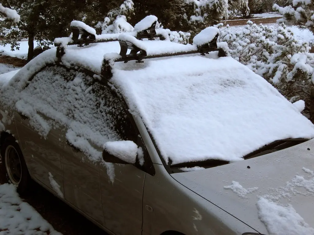 Close-up of a kayak roof rack strap being tightened on a car crossbar