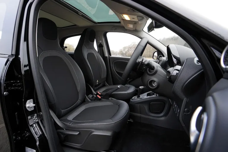 Three car seat cleaning sprays beside a car seat with a microfiber cloth in natural light.
