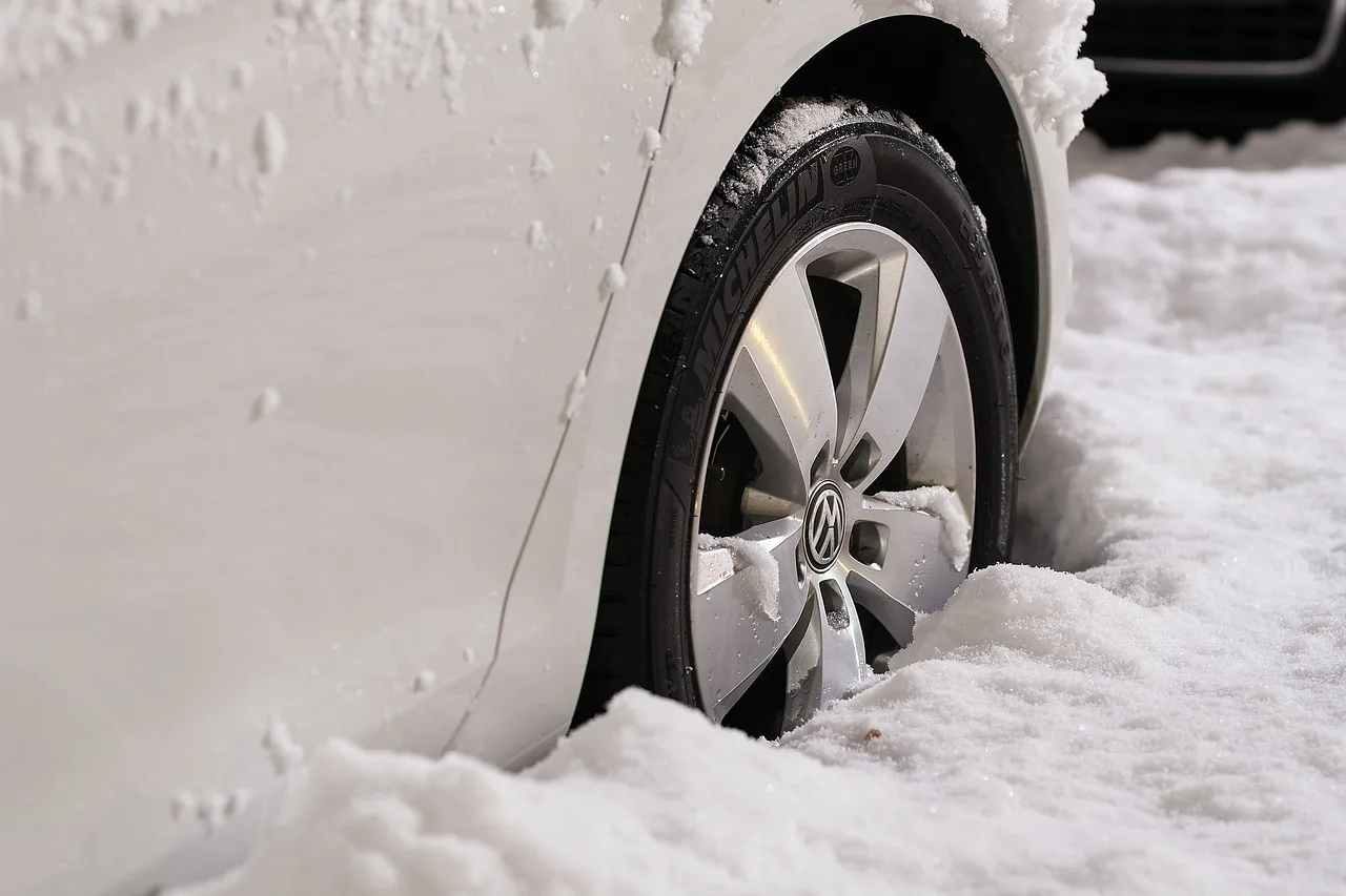 Driver comparing winter tire tread patterns beside a snow-dusted SUV on a frosty street