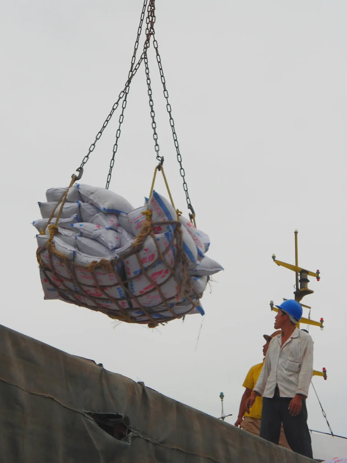 A gloved hand clips a cargo net hook to a truck bed anchor point