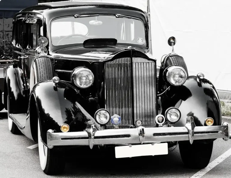 Chrome polish products beside a car bumper with reflective trim and detailing tools in daylight