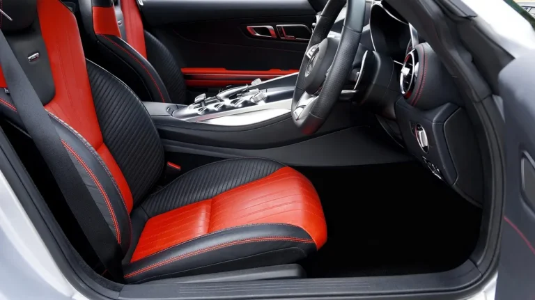 Leather car seats in shiny, natural, and matte finishes inside a sedan with cleaning supplies nearby