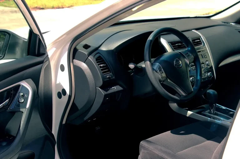 Car interior cleaning supplies on a front seat beside leather, fabric, and plastic surfaces