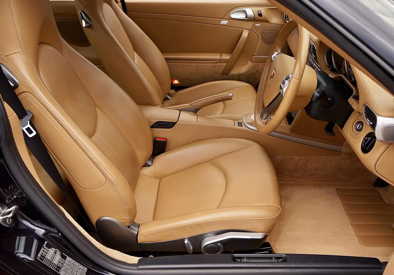 Three custom floor mats for cars laid out beside an open sedan door in natural light