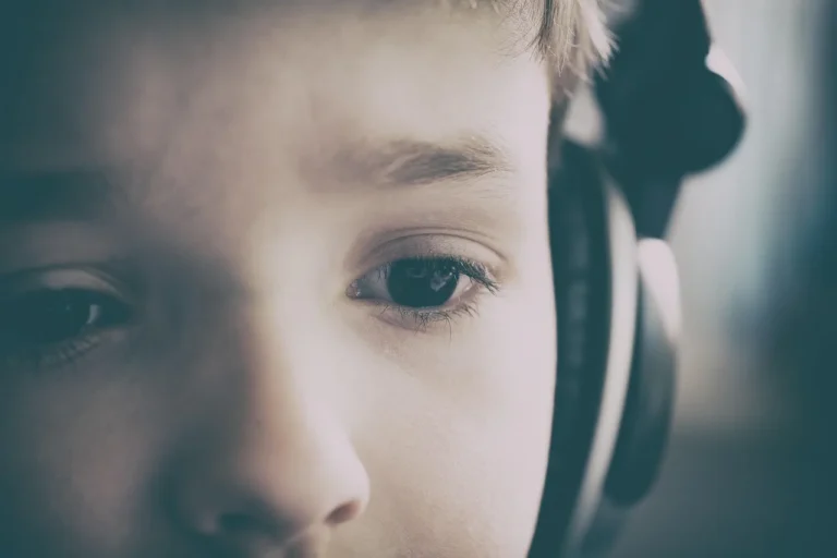 Two kids wearing headphones in the backseat of a car during a daytime road trip