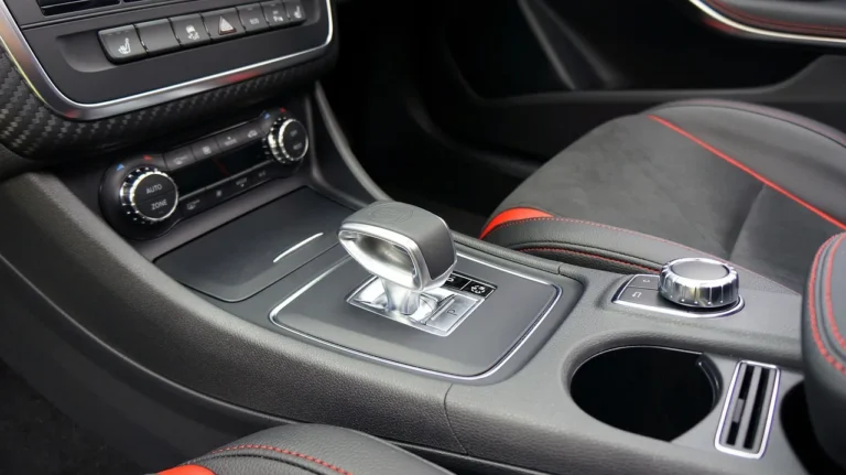 Two large car cup holder expanders in a console, holding a narrow bottle and a handled mug