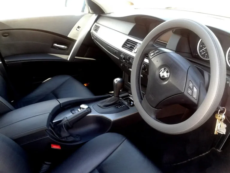 Leather cleaner being applied to a black car seat with a microfiber cloth in natural daylight